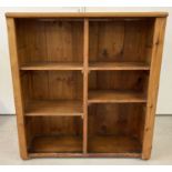 A pine storage unit/bookcase with 4 shelves at varying heights.