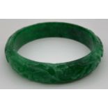 A green jade bangle with carved detail to outer surface. Approx. 7.5cm diameter. …