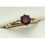 A silver gilt solitaire ring set with a round cut garnet. Marked 925 to inside of band. Stone app…