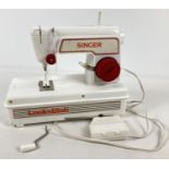 A child's Battery operated white and red plastic Lockstitch sewing machine by singer. Complete