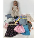 A modern Our Generation style vinyl doll with a collection of assorted handmade dolls clothes.
