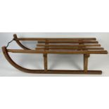 A vintage Davos Germina wooden sled with metal runners. Approx. 93cm long.
