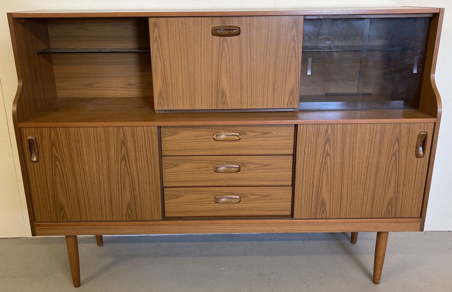 A vintage mid century Schreiber teak sideboard with sliding doors, drawers and glass shelves.