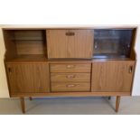 A vintage mid century Schreiber teak sideboard with sliding doors, drawers and glass shelves.