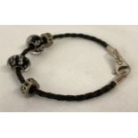 A silver and black plaited leather bracelet by Silverado, together with 4 charm beads.
