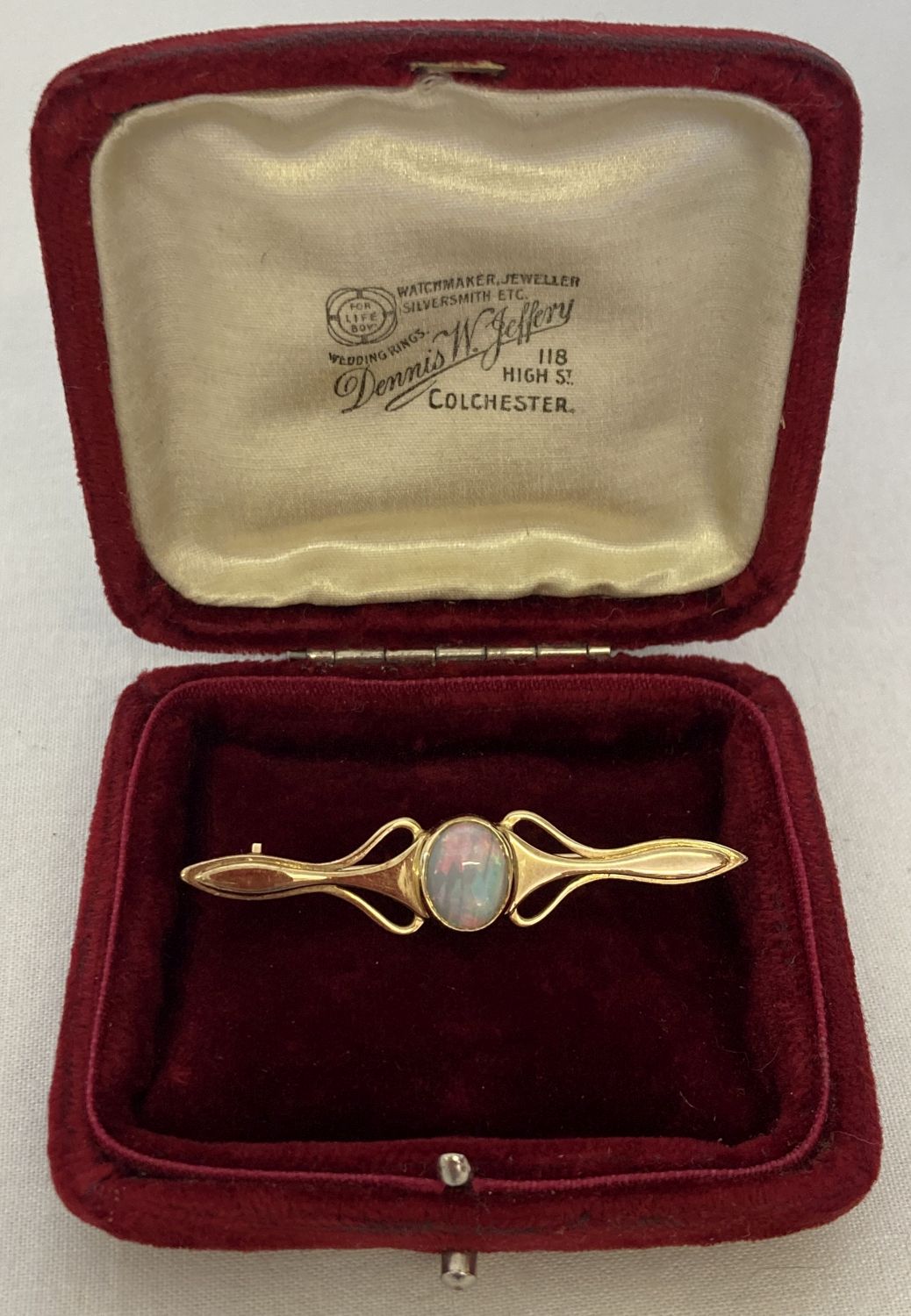 A gold Art Nouveau style bar brooch set with a central opal, tests as 9ct gold.