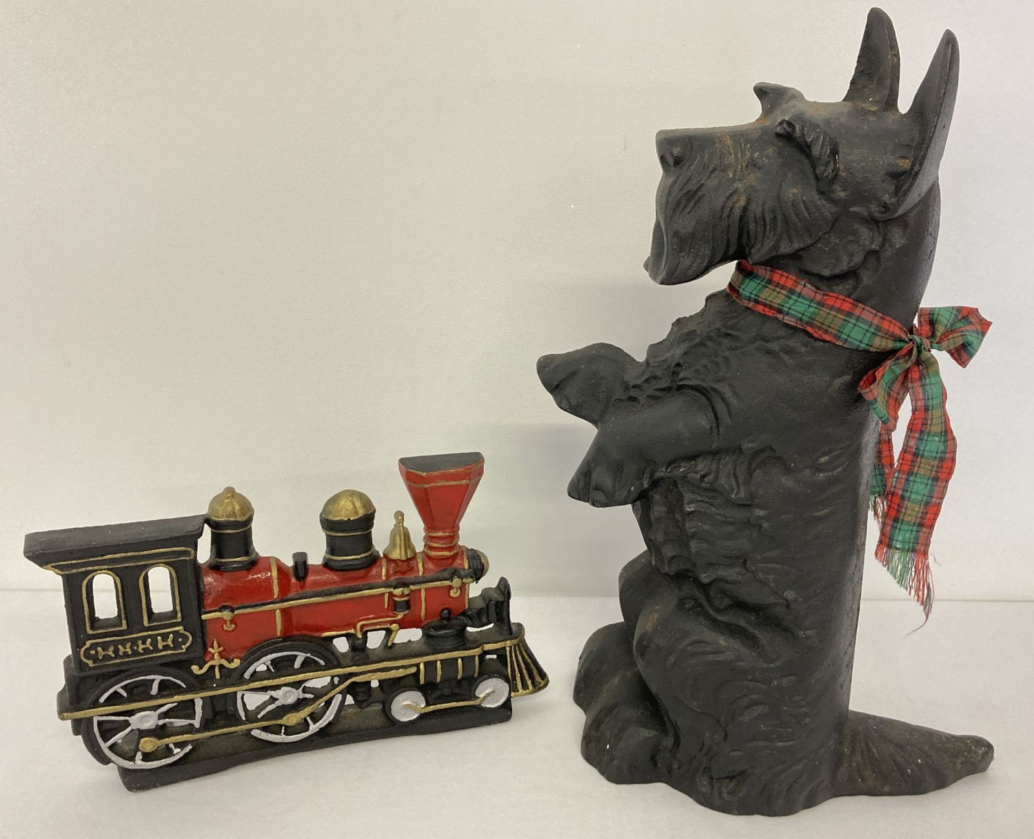 Two cast iron novelty doorstops, a steam train and a black Scottish Terrier.