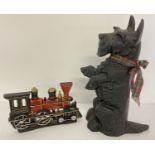 Two cast iron novelty doorstops, a steam train and a black Scottish Terrier.