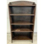 A vintage dark oak bookcase with adjustable shelves and carved detail to shaped top.