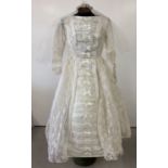 A 1960's wedding dress in a stiff polyester organza and lace. With headdress, veil and original box.