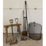 A collection of garden tools together with a metal fireguard and a wooden trestle.