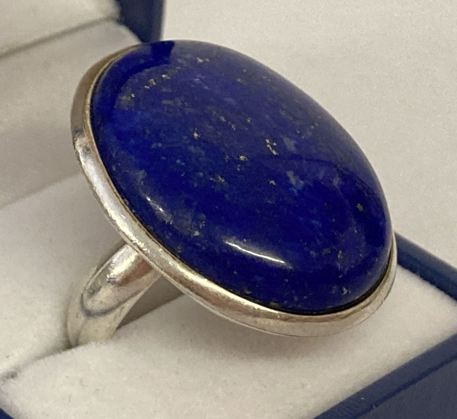 A modern silver statement dress ring set with a large oval lapis lazuli stone.