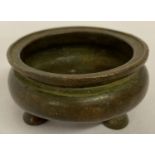 A small Chinese bronze censer with lipped rim and tripod feet.