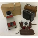 A boxed vintage slide projector together with 2 vintage cased cameras.