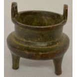 A miniature Chinese bronze censer with loop handles and raised on tapered tripod legs.