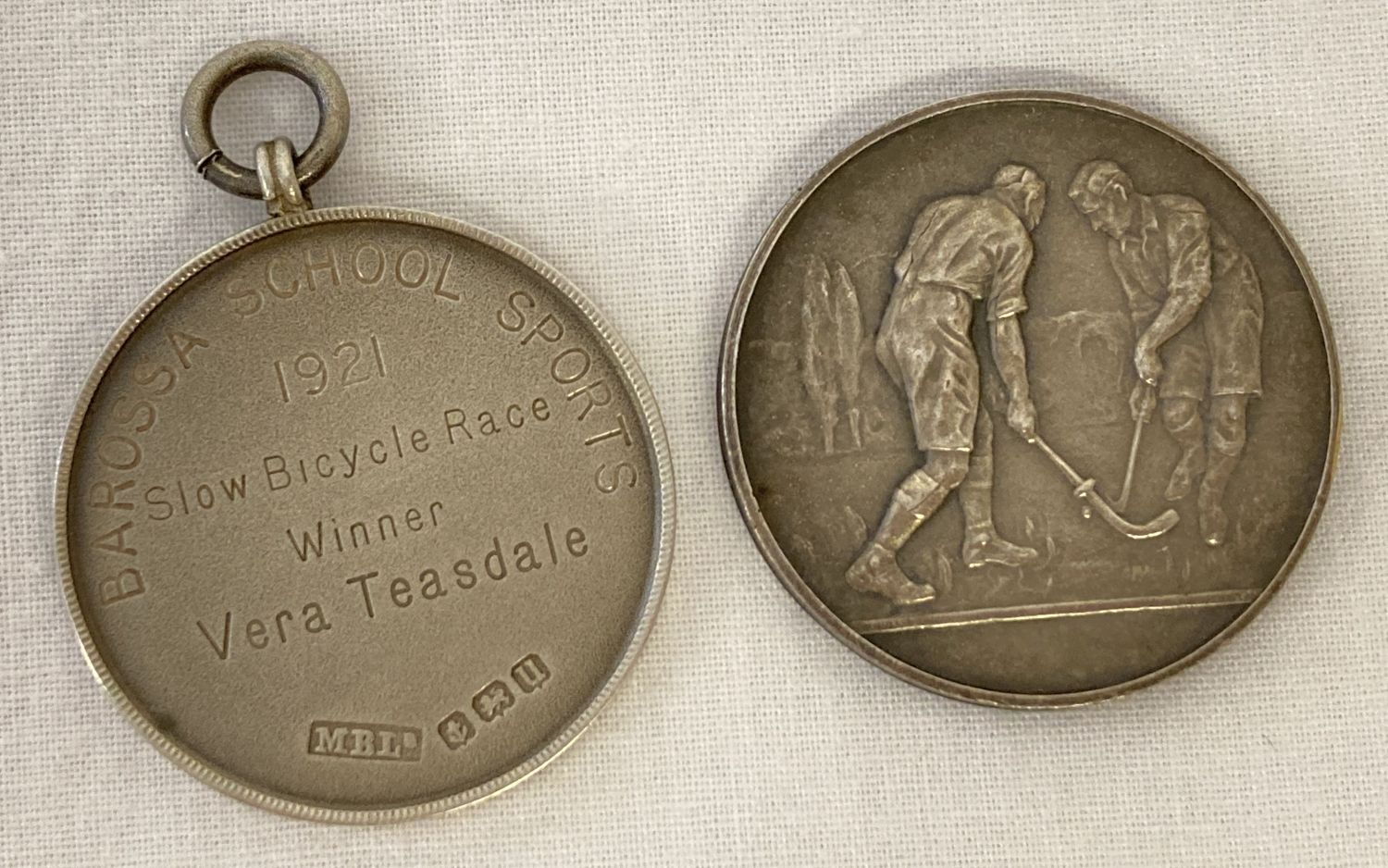 2 medals, an antique silver medal with laurel leaf detail to one side and inscription to the other.