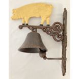 A painted cast metal wall hanging garden bell with pig design.