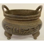 A large bronze censer with Arabic characters, loop handles and tripod feet.