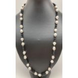 A 25" large freshwater pearl and onyx beaded necklace with silver tone S shaped hook clasp.
