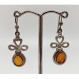 A pair of silver and amber, modern design, drop style earrings with heart detail to mounts. Backs