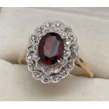 An 18ct yellow gold, diamond and garnet ring. Large oval cut central garnet surrounded by 2 rows