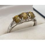 A 9ct white gold trilogy ring set with 3 round cut lemon citrine stones. In a decorative high