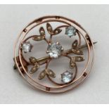 A Edwardian 9ct gold circular shaped pin back brooch with floral detail. Set with seed pearl and 4