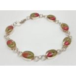 A silver panel bracelet set with real flowers. 8 oval shaped panels each set a small rose bud and