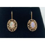 A pair of 9ct gold and opal drop earrings with hook wires. Central oval opal (approx. 6mm x 4mm)