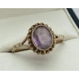 A 9ct gold and amethyst dress ring. A single oval cut amethyst with rope detail to mount. Ring