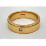 An 18ct gold 6mm band ring set with a single small square cut diamond. Ring size R, makers marks and