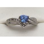 A 9ct white gold, diamond and tanzanite ring. A trillion cut tanzanite stone with a row of channel