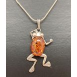 A silver frog shaped pendant set with an oval cognac amber cabochon, on a 15 inch fine snake chain