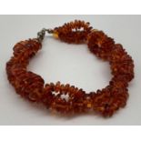 A modern triple strand plaited design cognac amber chip bracelet with lobster style clasp. Total