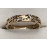 A 9ct gold band style ring with decorative scroll and foliate pierced work detail, set with 4