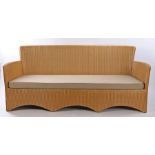 Lloyd Loom settee, with a rounded back and square frame arms above the undulating apron base,