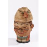 Carved and painted wooden tobacco jar and cover, depicting a squat figure wearing a tasseled hat,