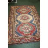 Middle Eastern carpet, the red ground with scroll decorated lozenge centre surrounded by