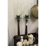 Pair of storm lanterns, the clear glass shades above palm tree form stems and square bases, 68cm
