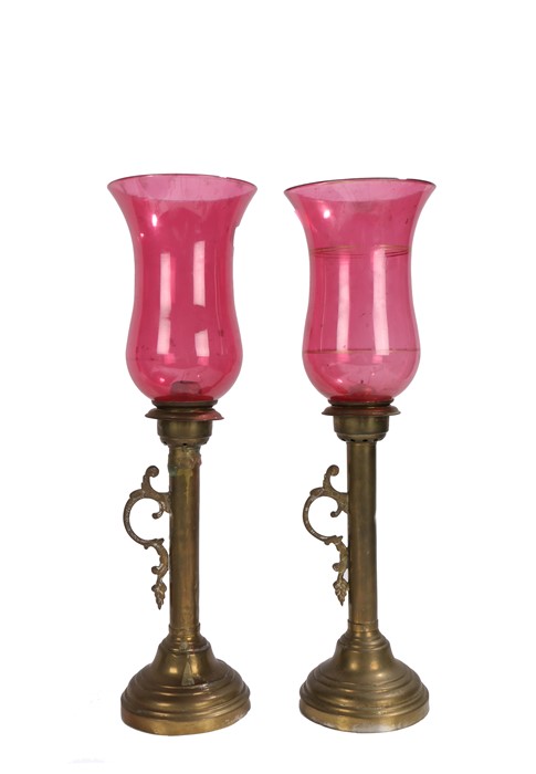 Pair of brass storm lanterns, with cranberry glass shades, 46cm high