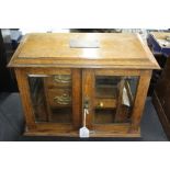 Edwardian oak smokers cabinet, the bevelled glazed doors opening to reveal three drawers, two open