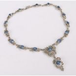 Silver necklace, set with round cut blue paste stones and clear stones to the scrolling necklace,