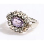 White metal ring, set with a central purple stone and paste surround, ring size L