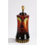 Moorcroft pottery lamp, in a deep rouge with grapes and leaves raised on a gilt metal base, 31cm