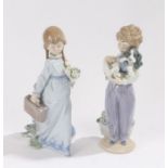 Two Lladro figures, depicting a boy and a girl, one holding a dog, the other holding a bunch of