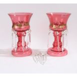 Pair of early 20th Century cranberry glass table lustre's, with floral gilt decoration and suspended