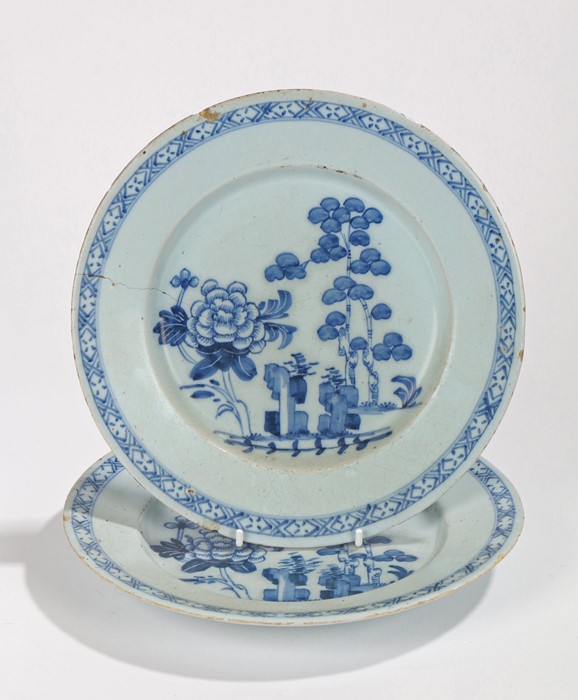 Pair of 18th Century Delft plates, with a large flower and tall trees to the centre, hatched cross