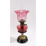 Late Victorian cranberry glass oil lamp, having cranberry glass shade and font, raised on brass