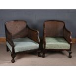 Pair of bergere armchairs, with cane backs and arms, over-stuffed seats, on claw and ball feet