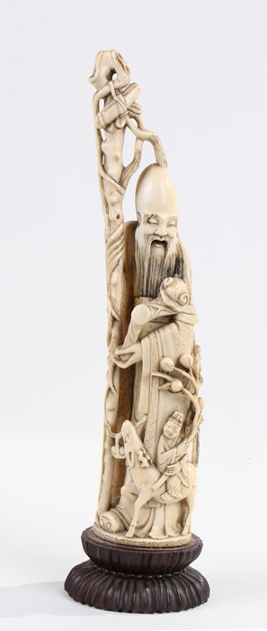 Japanese carved ivory immortal, Meiji period, wearing a flowing robe and holding a staff, raised